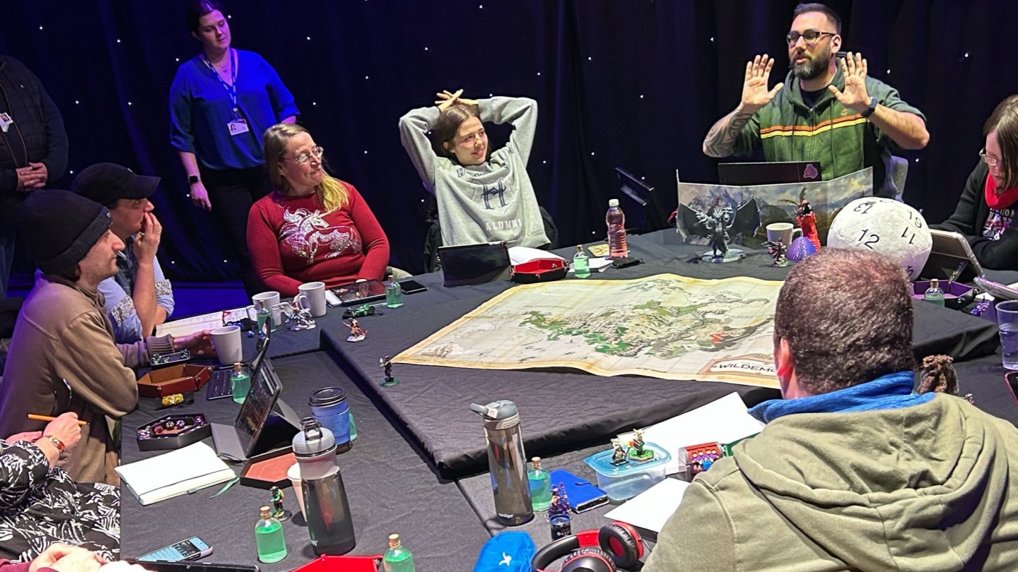 A group of people sitting around a table with a map laying on the table and discussing it