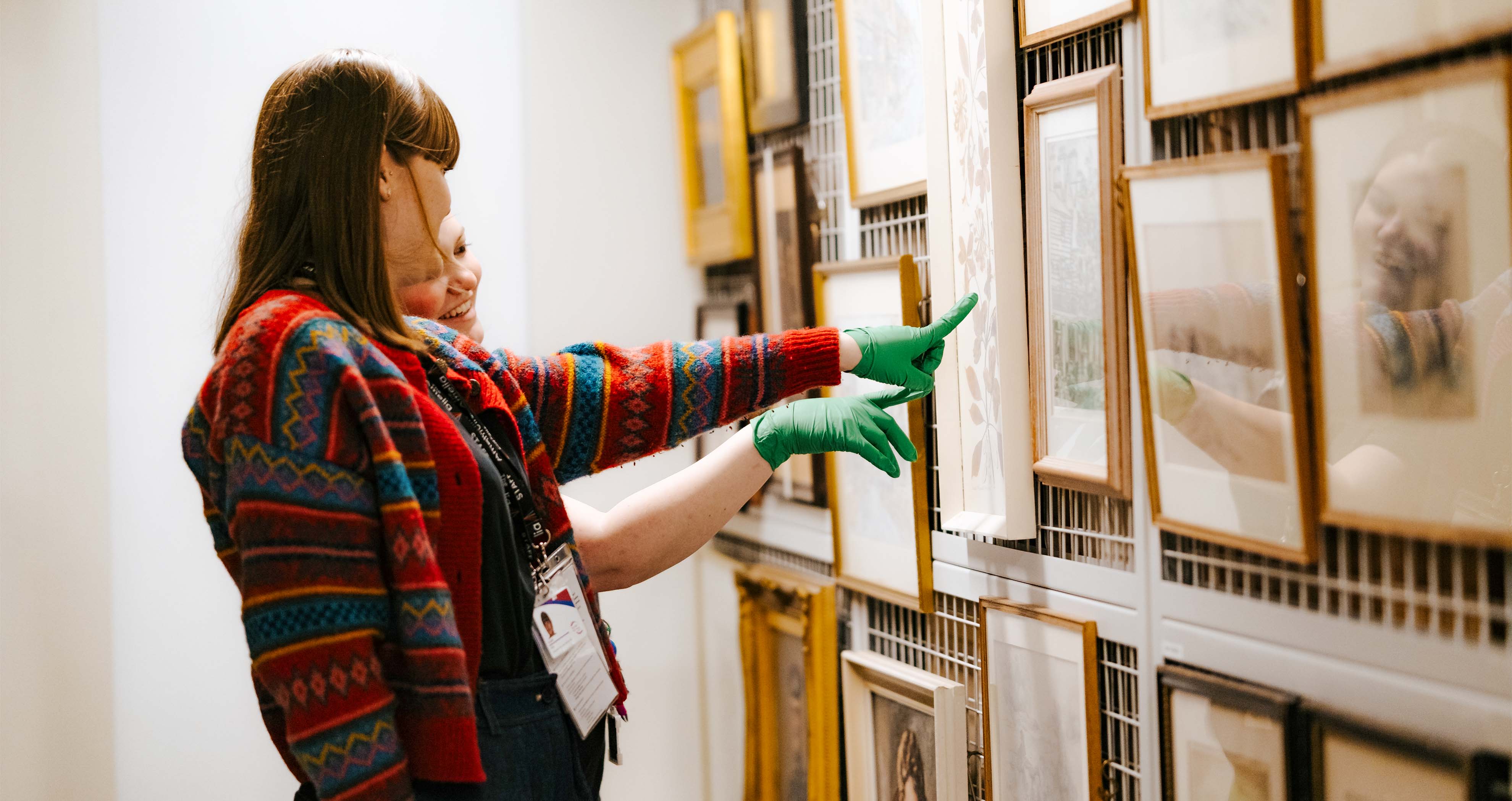 Two Amelia team members with gloves pointing at paintings