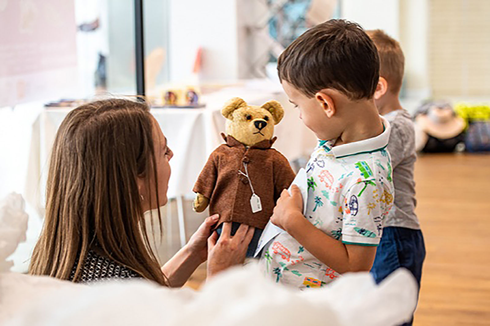 Families Adult and two children looking at an exhibit teddy bear
