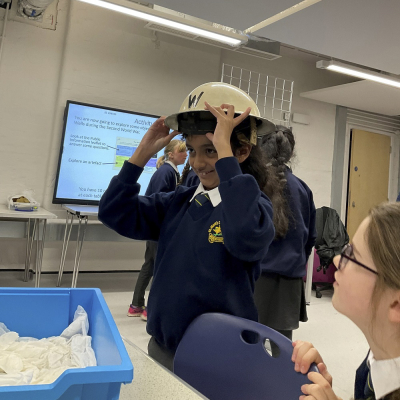 A child is trying on a WW2 air raid warden's helmet.