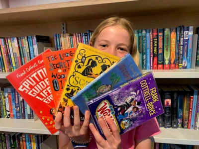 Girl holding up 5 Frank Cottrell-Boyce books