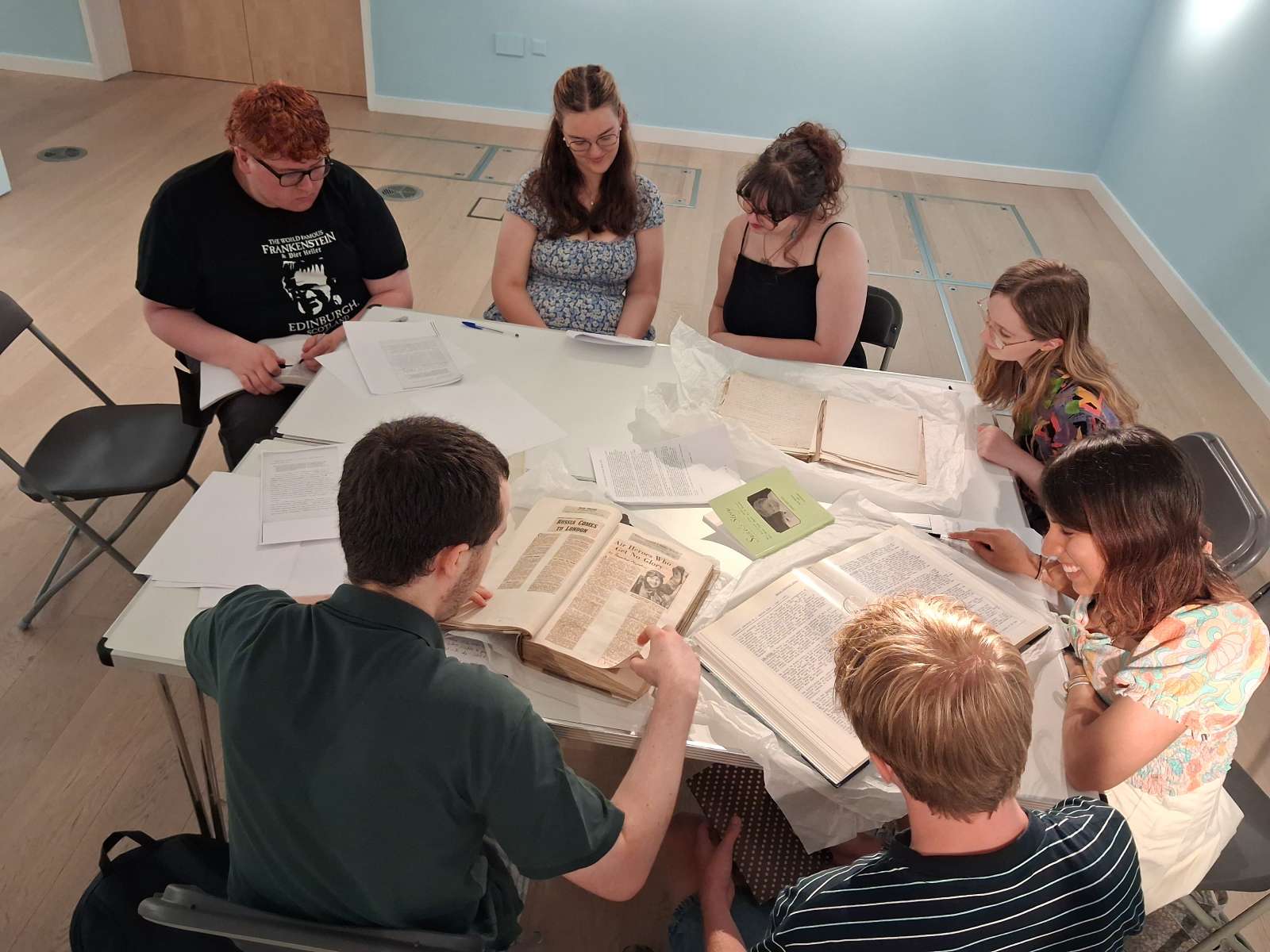 Young people sitting around a table looking at old books