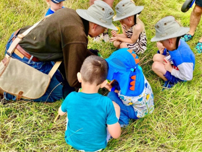 Children In the garden with an Amelia Scott team members studying items