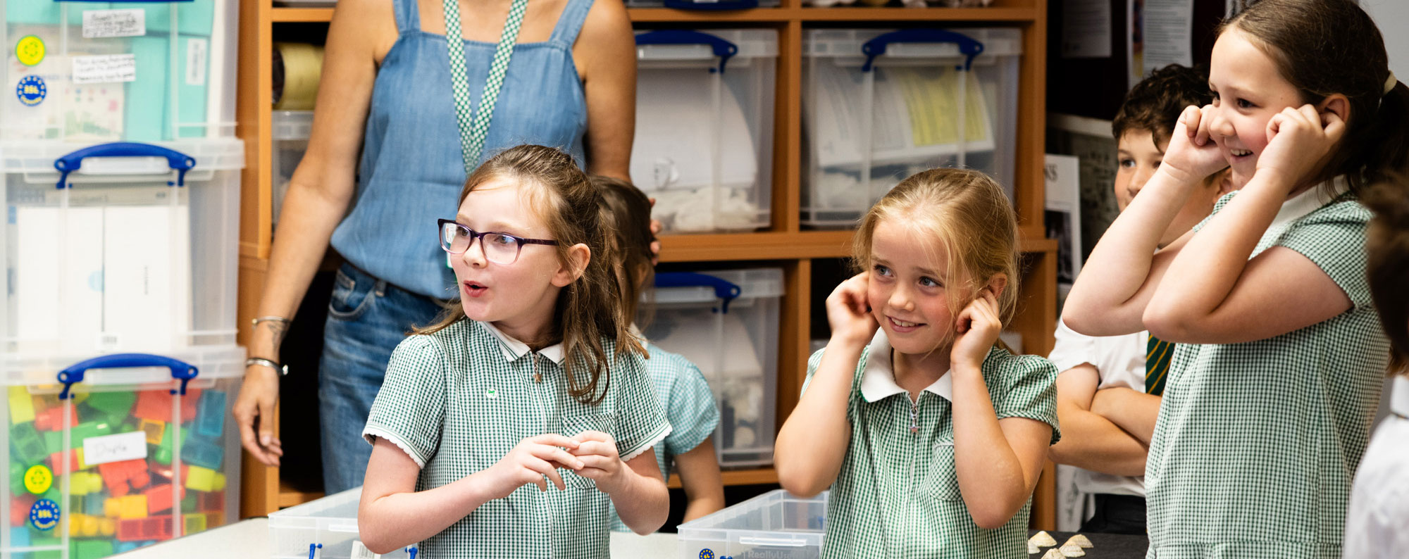 Children on a school visit with their fingers in their ears looking in wonder off to the left