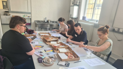 Young producers around a table working and eating pizza